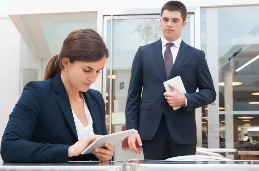 focused-business-woman-using-tablet-coworker-standing-near